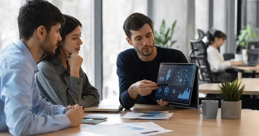 Profesionales analizan gráficos digitales de demanda laboral e inteligencia artificial en una mesa de trabajo, como imagen editorial sobre perfiles técnicos y habilidades requeridas por empresas argentinas.